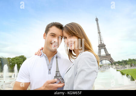 Paar steht vor dem Eiffelturm mit Souvenir Stockfoto