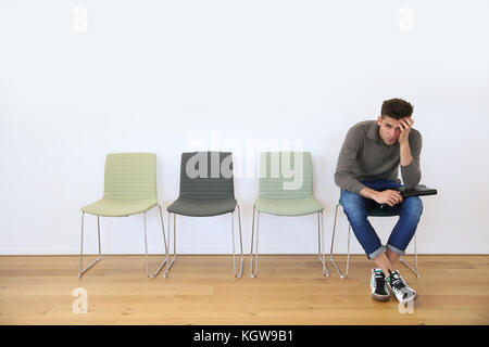 Junger Mann im Warteraum für Vorstellungsgespräch Stockfoto