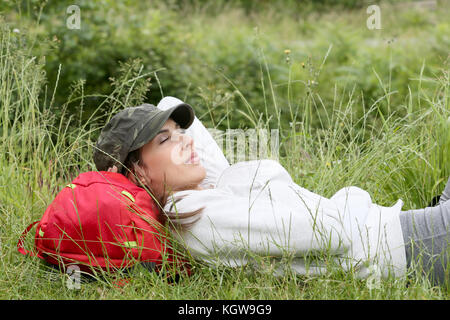 Junge Frau entspannen im Gras auf Wandertag Stockfoto