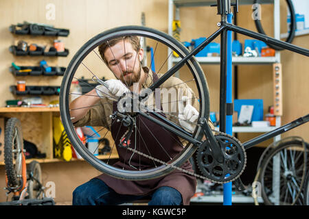 Professionelle Handwerker zur Festsetzung Kette auf Zahnrad am Arbeitsplatz Stockfoto