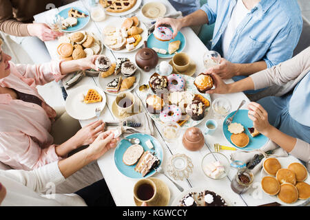 Freunde versammelt, zum Geburtstag Feier in frische, hausgemachte Puffs und Gebäck mit Tee bei Tisch serviert. Stockfoto