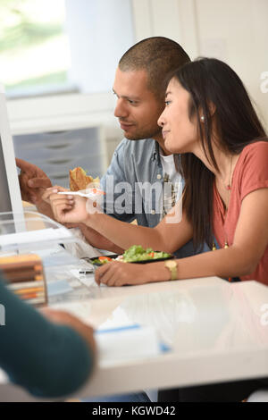 Büro - Arbeitnehmer mit Mittagessen im Büro vor der Desktop Stockfoto