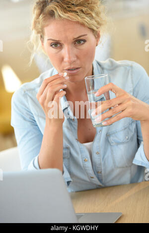 Frau bei der Arbeit unter Pille Kopfschmerzen zu erleichtern Stockfoto