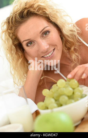 blonde Frau essen Trauben Stockfoto