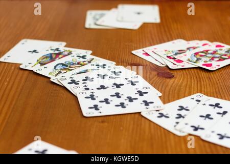 Prag, ca. Juli 2017 - Karten liegen auf hölzernen Tisch während einer wie Rummy card game. Sehr lange Folge von Clubs und einigen anderen verschmilzt. keine Decks in Aussicht Stockfoto