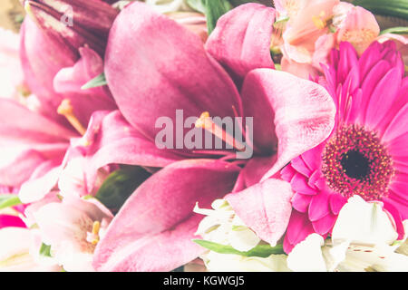 Ein Blumenstrauß aus Lilien, Gerbera, weiße Rosen und alstroemeria auf einem weißen Holztisch. Ein Urlaub, ein Geschenk Stockfoto