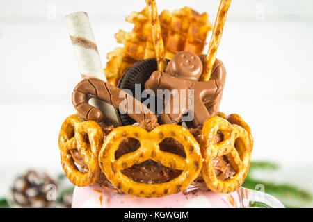 Freakshake von rosa Smoothie. monstershake mit Schokolade, Zuckerrohr, Brezeln, Gebäck, Waffeln und Eibisch. extreme Milchshake in einem Marmeladenglas. whi Stockfoto