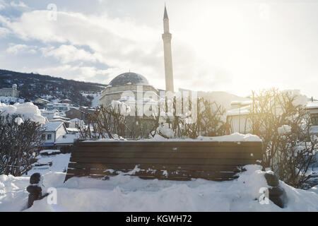 Holzparkbank mit Schnee bedeckt vor der sinan pascha Moschee in Prizren, Kosovo in der Wintersaison Stockfoto