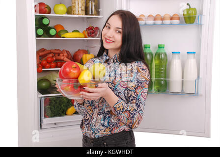 Gesunde Ernährung-Konzept. Ernährung. Schöne junge Mädchen in der Nähe der Kühlschrank mit gesunden Lebensmitteln. Obst und Gemüse in den Kühlschrank stellen. Veganes Essen Stockfoto