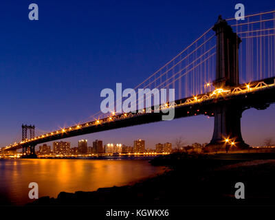 Eine Nachtaufnahme der Manhattan Bridge, aufgenommen in der Nacht und mit Blick über Manhattan von der Küste Brooklyns, New York, USA Stockfoto