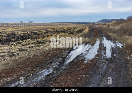 Landwirtschaftliche Landschaft mit Erde Straße neben geerntete Mais Feld in späten herbstlichen Jahreszeit in poltavskaya Oblast, Ukraine Stockfoto