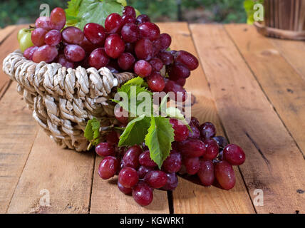 Korb der roten Trauben auf einer hölzernen Oberfläche Stockfoto