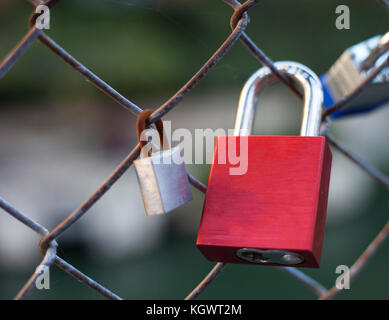 Rote Liebe Sperre befestigt Zaun neben einem rostigen Schloß zu Draht Stockfoto