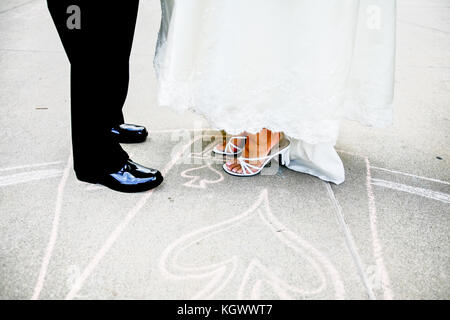 Unteren Körper Blick auf Braut und Bräutigam stehen auf einem Chalk herzen Zeichnung auf der Straße Stockfoto