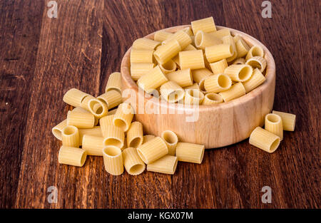 Italienische Pasta Mezze maniche auf hölzernen Hintergrund Stockfoto