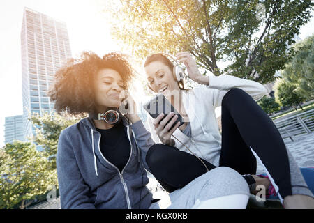 Mädchen im Sport Outfit, das Hören von Musik auf dem Smartphone Stockfoto