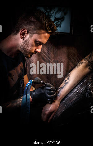 Professionelle Tätowierer macht ein Tattoo auf die Hand eines jungen Mannes Stockfoto