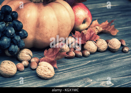 Kürbis, Apfel, Nüsse, Beeren mit Ahorn Blätter auf Holz- Hintergrund. Herbst Karte Danksagung. Halloween. Vintage Farben Stockfoto