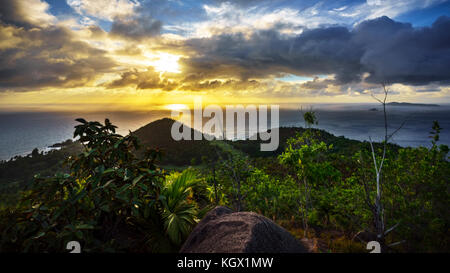 Sonnenuntergang hinter Wolken über zwei Hügel auf den Seychellen. Auf der Suche nach einem Berg. Stockfoto