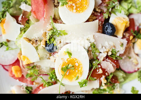 In der Nähe von frischem Salat mit gekochten Eiern, Gemüse und Parmesan, Ansicht von oben Stockfoto