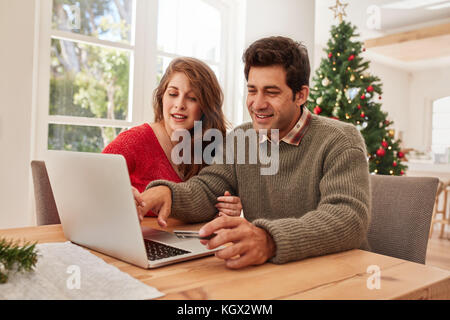 Glückliches junges Paar mit Kreditkarte online einkaufen. Junger Mann und Frau mit Laptop und Kreditkarte online einkaufen. Online christmas shopping. Stockfoto