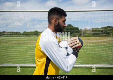Seitenansicht der Torwart halten Fußball vor Ziel post Stockfoto