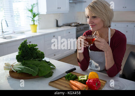 Schöne Frau mit Zitrone Kaffee am Tisch in der Küche Stockfoto