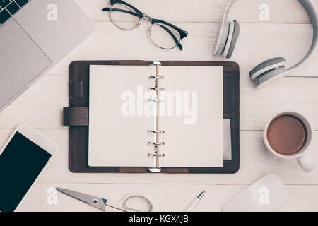 Draufsicht auf geöffnet Notebook, Smartphone, Laptop, Brillen, Tasse Kaffee und andere Geräte auf Holz Büro Schreibtisch. Stockfoto