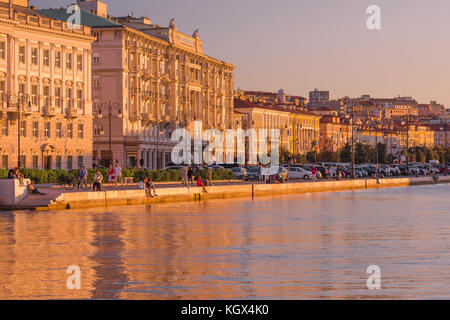 Triest Uferpromenade, Blick auf einen Sonnenuntergang im Sommer, der die Hotels entlang der Küste - die Riva del Mardracchio - in Triest, Italien, beleuchtet. Stockfoto