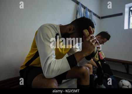 Traurig fußball Spieler sitzt auf der Bank in der Umkleidekabine Stockfoto