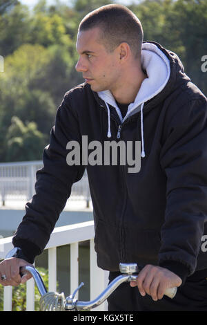 Ein junger Mann, gopnik, sitzt auf einem Fahrrad Stockfoto