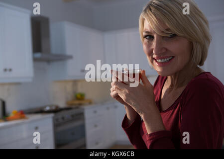 Portrait von glücklichen Frau, die Zitrone Tee in der Küche Stockfoto