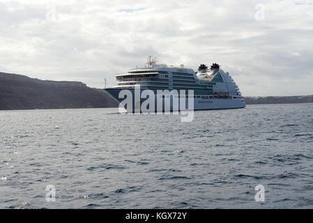 Kreuzfahrtschiff vor der Küste von Santorini an einem bewölkten Tag. Stockfoto