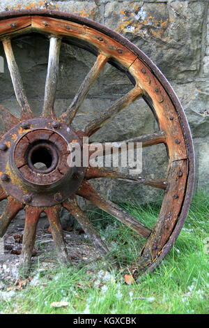 Alte Holz- und Metall wagon wheel lehnte sich auf Wand Stockfoto