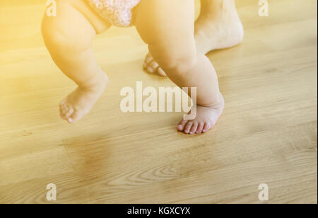 Baby und Mutter Füße sind zu Fuß auf dem hölzernen Fuss. Traum unscharf. Stockfoto