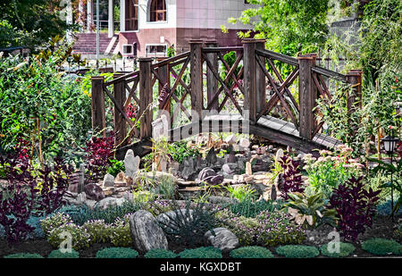 Landschaft: kleine Holzbrücke über einen künstlichen Teich mit Steinen und Pflanzen dekoriert Stockfoto