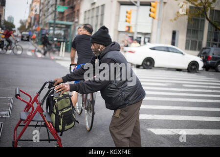 NEW YORK CITY, NY, USA - Oktober 2017 - unbekannter Mann über die Straße mit einem assist Stuhl Stockfoto