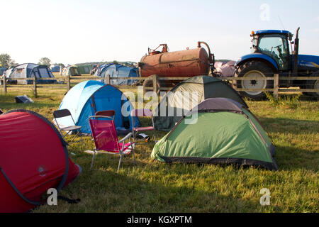 Zelte bei einem Musikfestival mit Traktor und Tanker im Hintergrund Stockfoto