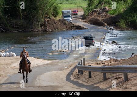 Puerto Ricaner überqueren einen überfluteten Fluss mit Fahrzeugen und zu Pferd, nachdem eine Brücke nach dem Hurrikan Maria am 4. November 2017 in Morovis, Puerto Rico, einstürzte. (Foto von Andrea Booher über Planetpix) Stockfoto