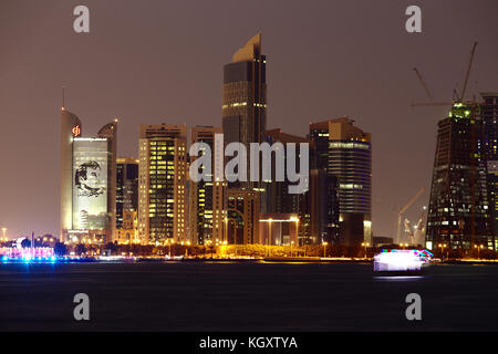 Doha, Katar - November 11, 2017: City Skyline bei Nacht mit Turm der Commercial Bank und Poster von Emir tamim Bin Hamad auf der linken Seite. hell beleuchteten Stockfoto