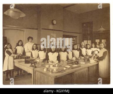 Originalfoto des Edwardianischen Mädchen in einem Hauswirtschaft Klasse, lernen Backen und Kochen in der Küche, um 1910, Großbritannien Stockfoto