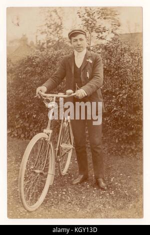 Original Vintage Cycling Edwardian Postkarte eines älteren Jungen, der sein Fahrrad in der Hand hielt, um 1908 Stockfoto