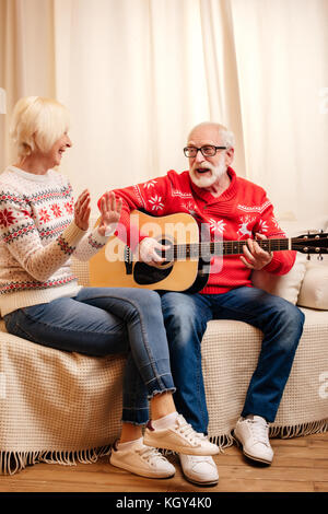 Älterer Mann spielt auf der Gitarre für Frau Stockfoto