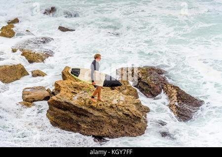 Ein surfer Schritte vorsichtig auf Felsen und in Gefährliche Brandung Bedingungen am Bronte Beach in Sydney, NSW, Australien Stockfoto