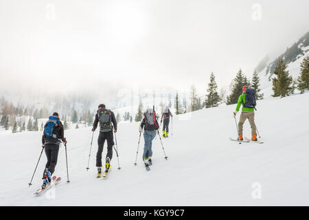 Gruppe von zurück Langläufer gehen durch einen nebligen Tal. Stockfoto