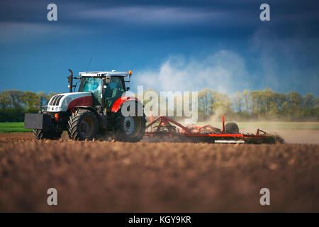 Bauer im Traktor Vorbereitung land mit saatbeet Kultivator, Sonnenuntergang geschossen Stockfoto