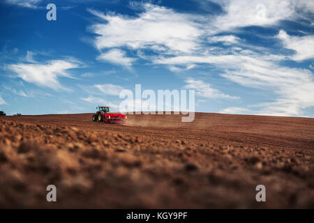 Bauer im Traktor vorbereiten Ackerland mit Saatgut für das nächste Jahr Stockfoto