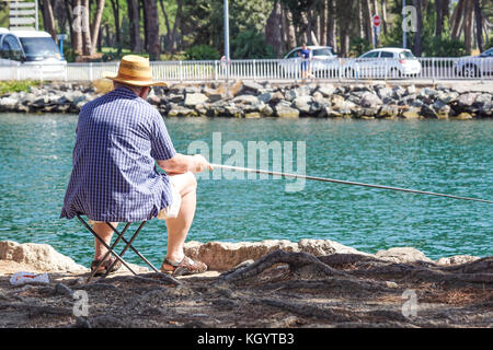 Pensionierte ältere Mann genießt Angeln vom Steg in den Fluss Stockfoto