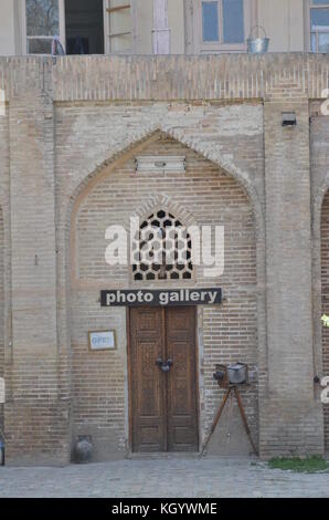 Eine altmodische Kamera auf Stativ stand vor einer Fotogalerie in Buchara, Usbekistan. alte Holztür mit islamischen Muster geschnitzt ist gesperrt. Stockfoto