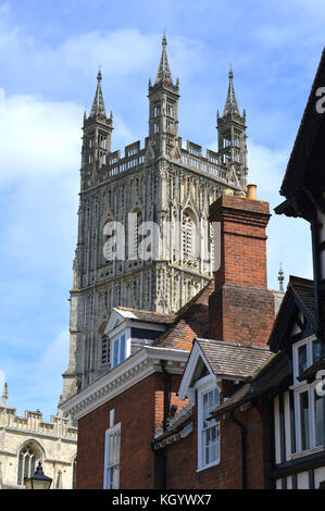 Die Kathedrale von Gloucester vor einem blauen bewölkten Himmel über in der Nähe Dächer. Stockfoto